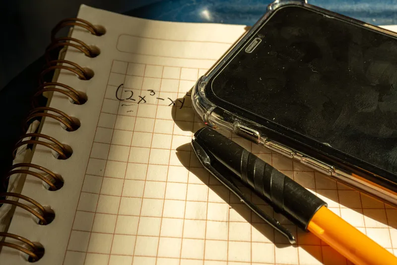 Cuaderno con una ecuación y un móvil